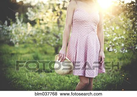 Woman holding hat in rural orchard View Large Photo Image Stock Photo - Woman holding hat in rural orchard. Fotosearch