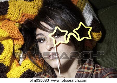 Stock Image - Woman holding star-shaped eyeglasses. Fotosearch