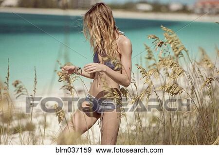 Stock Photo - Woman in bikini walking in beach grass. Fotosearch