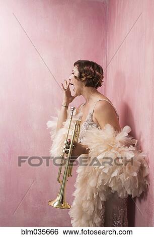 Stock Photograph - Woman in feather boa holding trumpet. Fotosearch