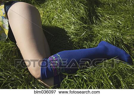 Stock Photo - Woman in knee socks laying in grass. Fotosearch