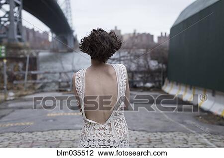 Woman in low-back dress walking in industrial area View Large Photo Image Stock Image - Woman in low-back dress walking in industrial area. Fotosearch