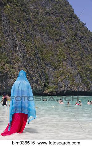 Stock Photograph - Woman in traditional headscarf standing on beach. Fotosearch