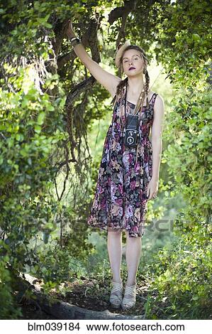 Picture - Woman in vintage dress climbing tree. Fotosearch