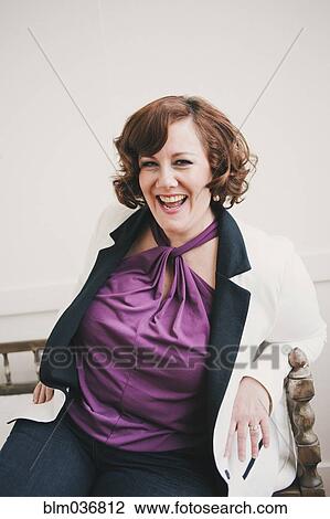 Stock Image - Woman laughing on wooden bench. Fotosearch