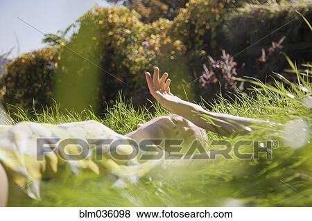 Stock Photo - Woman laying in tall grass in park. Fotosearch