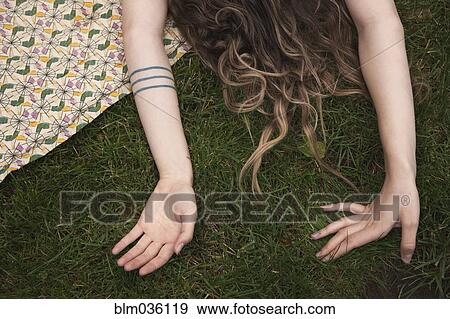 Stock Photo - Woman laying on blanket in grass. Fotosearch