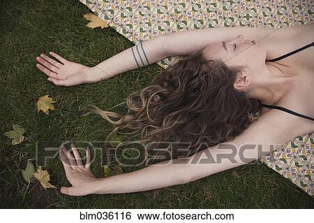 Stock Photograph - Woman laying on blanket in grass. Fotosearch