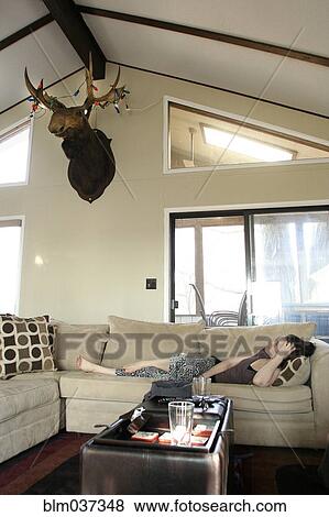 Woman laying on sofa in living room View Large Photo Image Stock Photo - Woman laying on sofa in living room. Fotosearch