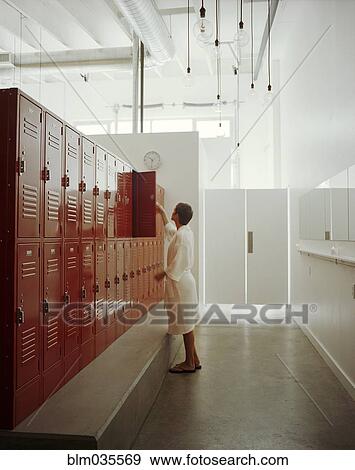 Woman opening locker in locker room View Large Photo Image Stock Photo - Woman opening locker in locker room. Fotosearch