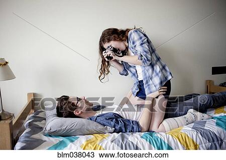 Woman photographing boyfriend on bed View Large Photo Image Stock Image - Woman photographing boyfriend on bed. Fotosearch