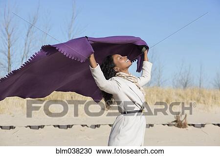 Stock Image - Woman playing with fabric on beach. Fotosearch