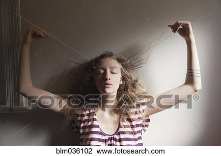 Stock Image - Woman playing with her hair in sunlight. Fotosearch