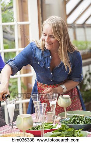 Woman pouring champagne glasses on dinner table in greenhouse View Large Photo Image Stock Photo - Woman pouring champagne glasses on dinner table in greenhouse. Fotosearch