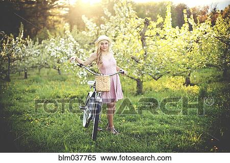 Stock Photography - Woman pushing bicycle in rural field. Fotosearch