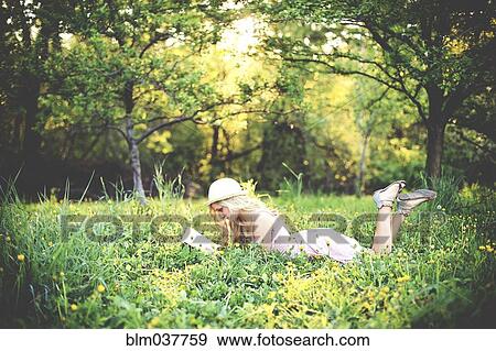Stock Photo - Woman reading book and laying in rural field. Fotosearch