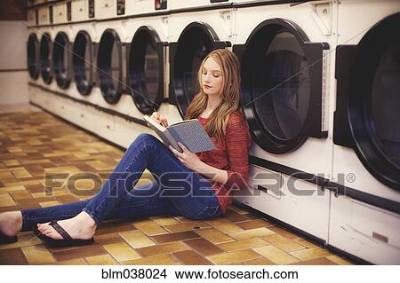 Woman reading book at laundromat View Large Photo Image Picture - Woman reading book at laundromat. Fotosearch
