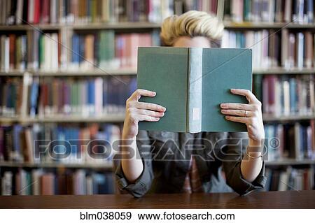 Stock Photo - Woman reading book in library. Fotosearch