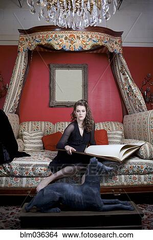 Woman reading oversized book on sofa in ornate living room View Large Photo Image Picture - Woman reading oversized book on sofa in ornate living room. Fotosearch