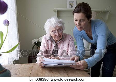Woman reading to mother at table View Large Photo Image Stock Photograph - Woman reading to mother at table. Fotosearch