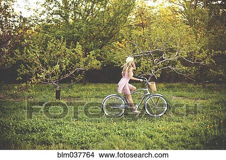 Picture - Woman riding bicycle in rural field. Fotosearch
