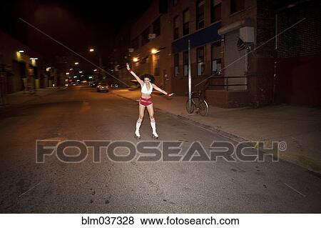 Stock Photo - Woman roller skating on street at night. Fotosearch