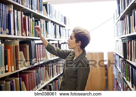 Stock Image - Woman searching for book in library. Fotosearch
