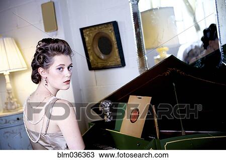 Woman sitting at piano in ornate living room View Large Photo Image Stock Image - Woman sitting at piano in ornate living room. Fotosearch