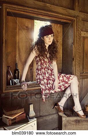 Stock Image - Woman sitting in barn window. Fotosearch