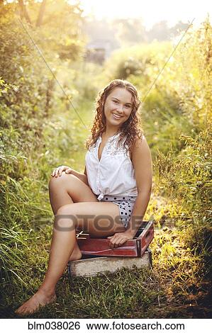 Stock Photograph - Woman sitting on crates in garden. Fotosearch