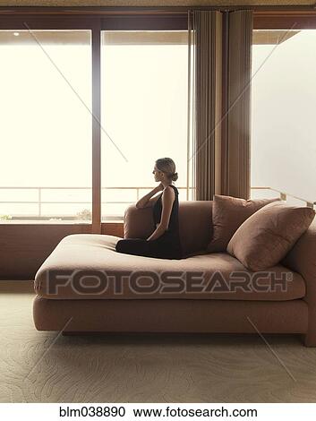 Woman sitting on sofa in modern living room View Large Photo Image Stock Image - Woman sitting on sofa in modern living room. Fotosearch