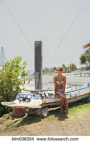Picture - Woman sitting on traditional canoe. Fotosearch
