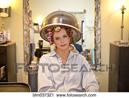 Woman sitting under hair dryer in salon View Large Photo Image Stock Image - Woman sitting under hair dryer in salon. Fotosearch