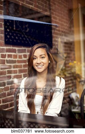 Stock Image - Woman smiling behind window in cafe. Fotosearch