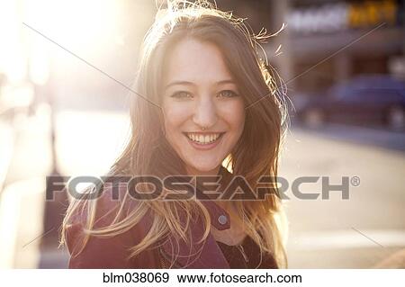 Stock Photo - Woman smiling on sunny city sidewalk. Fotosearch