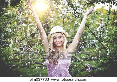 Stock Image - Woman standing in flowering trees. Fotosearch