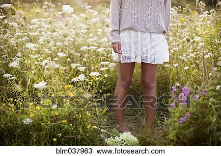 Stock Image - Woman standing in tall flowers. Fotosearch