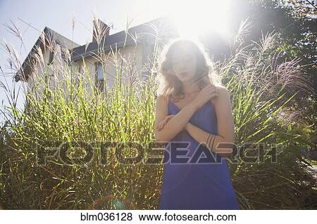 Woman standing near tall plants in backyard View Large Photo Image Stock Photo - Woman standing near tall plants in backyard. Fotosearch