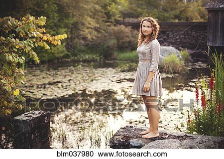 Woman standing on rock overlooking rural pond View Large Photo Image Stock Image - Woman standing on rock overlooking rural pond. Fotosearch