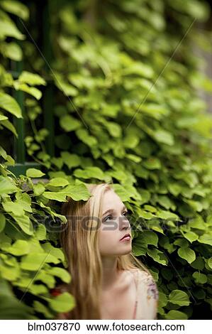 Stock Image - Woman standing under ivy wall. Fotosearch