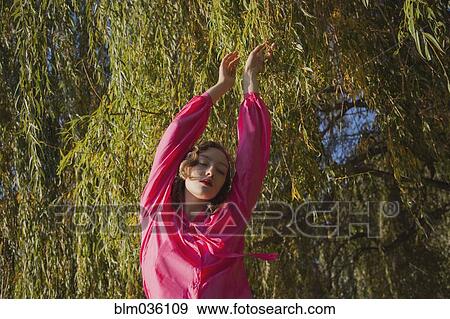 Woman standing under tree in park View Large Photo Image Stock Photo - Woman standing under tree in park. Fotosearch