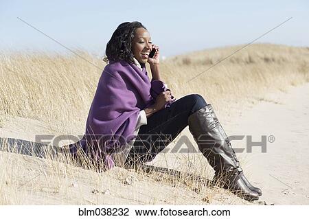 Stock Image - Woman talking on cell phone on beach. Fotosearch