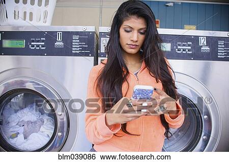 Woman using cell phone at laundromat View Large Photo Image Stock Photograph - Woman using cell phone at laundromat. Fotosearch