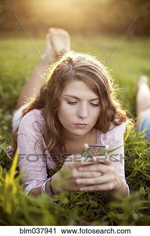 Stock Image - Woman using cell phone in rural field. Fotosearch