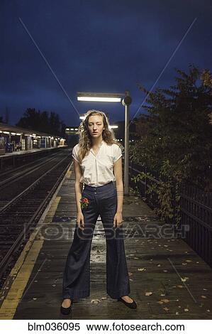 Stock Photography - Woman waiting for train at train station at night. Fotosearch