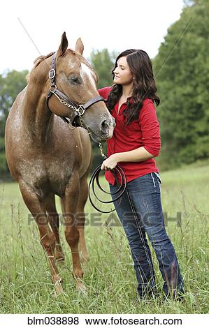 Stock Photo - Woman walking horse in rural field. Fotosearch