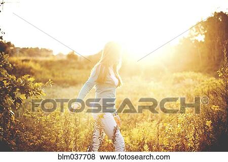 Woman walking in sunny field View Large Photo Image Stock Photo - Woman walking in sunny field. Fotosearch