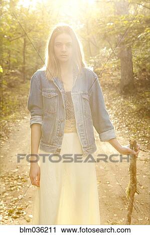Stock Image - Woman walking on dirt path in forest. Fotosearch