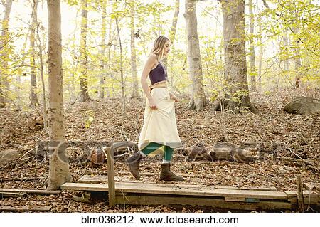 Woman walking on wooden walkway in forest View Large Photo Image Stock Image - Woman walking on wooden walkway in forest. Fotosearch
