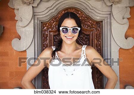Picture - Woman wearing sunglasses near decorative window. Fotosearch